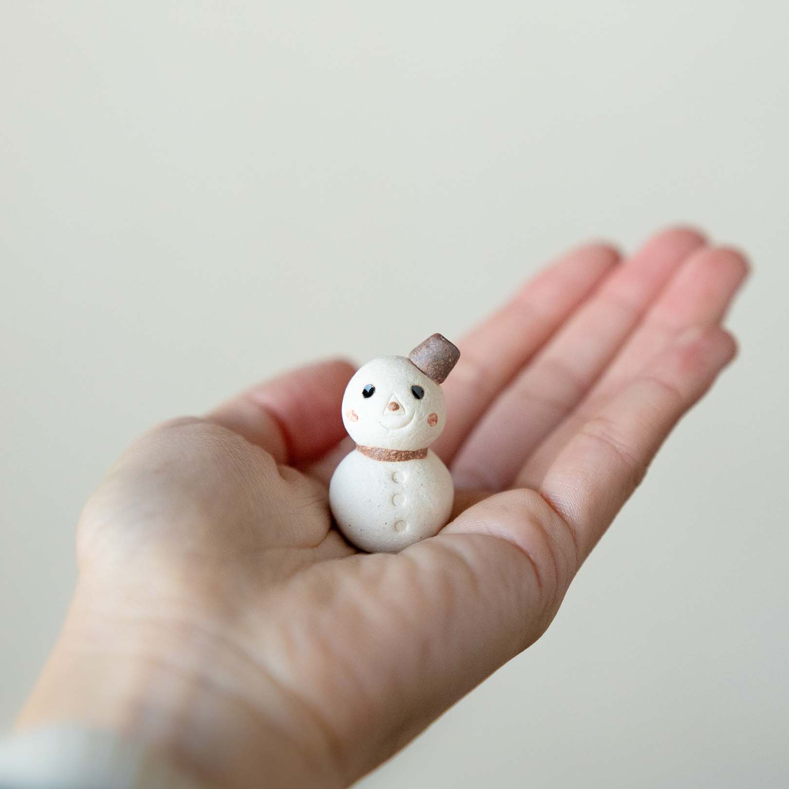 手のひらに乗せた陶器の小さな雪だるま