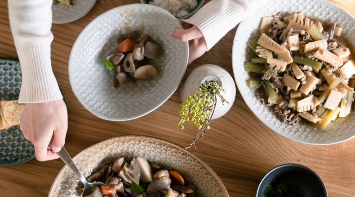 煮物を盛り付けた大皿から料理を取り分ける人